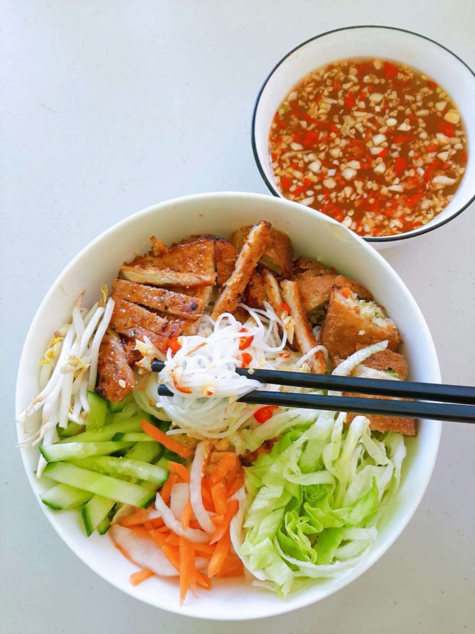Grilled pork on noodles with vegetables and dipping sauce.